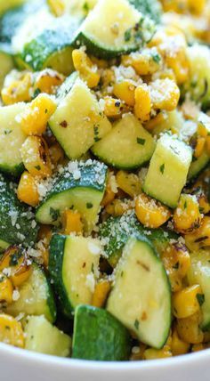 a white bowl filled with cucumber and corn salad on top of a table