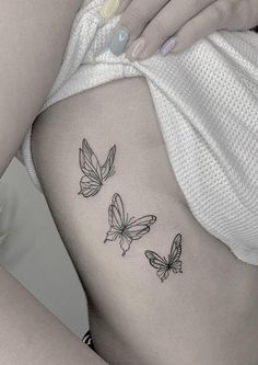 a woman's stomach with three butterflies on the lower back side ribcage