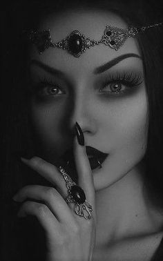 black and white photograph of a woman with dark makeup holding her hand to her face