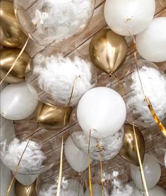 white and gold balloons are hanging from the ceiling in front of wooden planked walls