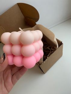 a hand holding a pink balloon in front of an open box