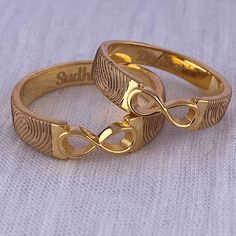 two gold wedding rings sitting on top of each other