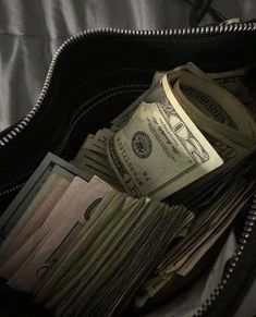 a wallet filled with money sitting on top of a bed