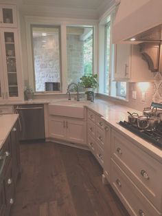 a kitchen with wooden floors and white cabinets, an oven, dishwasher and sink