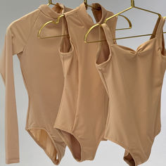 three tan shirts hanging on a clothes rack