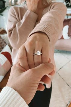 a woman holding the hand of another person with a diamond ring on her finger, in front of a mirror