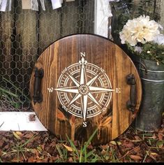 a cat is sitting in front of a wooden compass board with flowers on the side