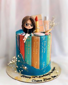 a cake decorated with books and a doll on top