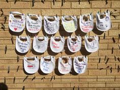 baby bibs hanging on a brick wall with writing and magnets attached to them