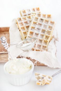 two waffles on a wooden tray with butter and a spoon next to them