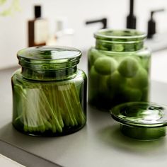 two jars filled with pickles sitting on top of a counter