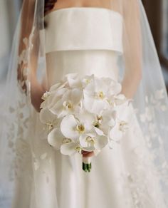 a bride holding a bouquet of white flowers