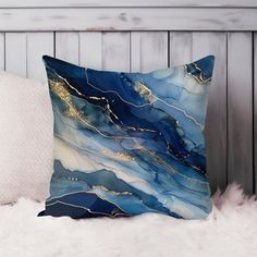 a blue and gold pillow sitting on top of a white furnishing covered bed