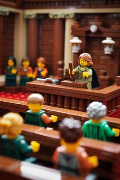 lego people sitting at desks in a courtroom, with one person holding a microphone