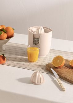 an orange juicer sitting on top of a table next to bowls of oranges