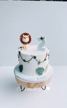 a white cake with a lion on top and two candles in the shape of numbers