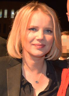 a woman with blonde hair wearing a black shirt and red scarf next to a bald headed man