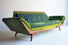 a green and blue couch sitting on top of a white floor next to a window