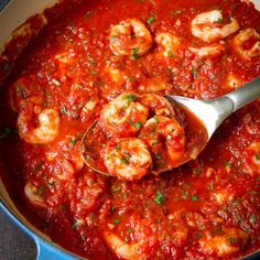 shrimp and tomato sauce in a pot with a ladle scooping up some food