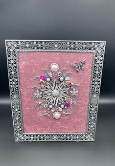 a pink and silver frame with an intricate design on the front, surrounded by butterflies