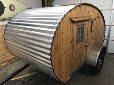 a small metal trailer sitting in a garage next to a surfboard