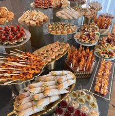 a table topped with lots of trays filled with different types of foods and desserts