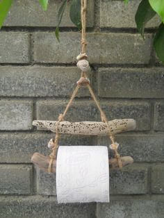 a roll of toilet paper hanging from a rope on a brick wall next to a tree branch