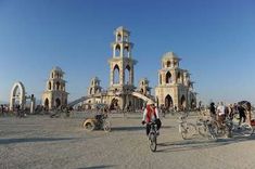 a person riding a bike in front of an old building with many bicycles parked near by