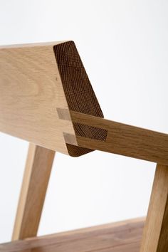 the back side of a wooden chair with wood grained seat and armrests