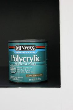 a can of polycryllic paint sitting on top of a black shelf next to a white wall