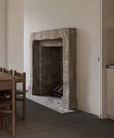 a fireplace in the middle of a room with a table and chairs next to it