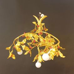 a chandelier with gold leaves and white balls hanging from it's center