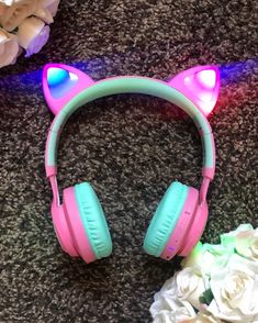 a pair of pink and blue cat ears headphones on top of a flower bouquet