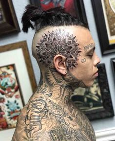 a man with tattoos on his head and neck is standing in front of some pictures