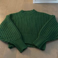 a green sweater is laying on the floor