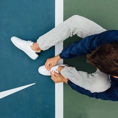 a man sitting on top of a tennis court next to a blue and white court