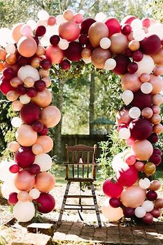 a chair sitting under an arch made out of balloons