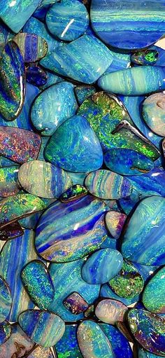 blue and green glass pebbles are stacked on top of each other in a pile together