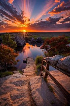 the sun is setting over a body of water with rocks and trees on either side