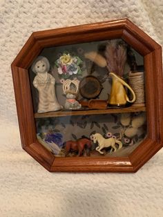 a wooden shelf filled with figurines and knick - knacks on top of a white blanket