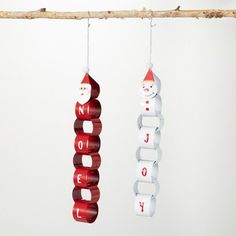 two christmas ornaments hanging from a tree branch with the word noel spelled in red and white