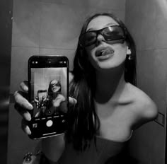 a woman taking a selfie in the mirror with her cell phone while wearing sunglasses