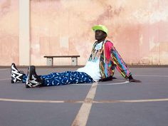 a man sitting on top of a basketball court next to a wall with graffiti painted on it