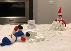 two elfs sitting on top of a bed with marshmallows and snowmen