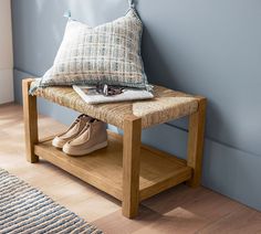 a pair of shoes sitting on top of a wooden bench next to a pillow and rug