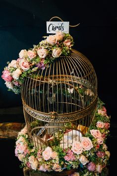 a bird cage with flowers and cards on top