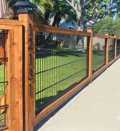 a wooden fence with black iron fencing on the top and bottom, in front of a house