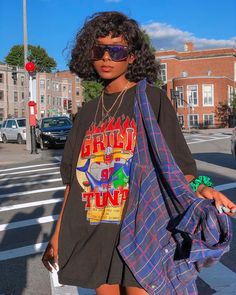 a young woman is standing on the street with her hand in her pocket and wearing sunglasses