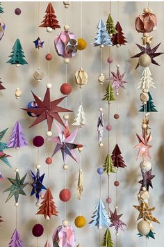 an origami christmas tree mobile hanging from strings with balls and ornaments on it