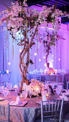 the table is set up for an event with flowers and candles on it, as well as hanging chandeliers